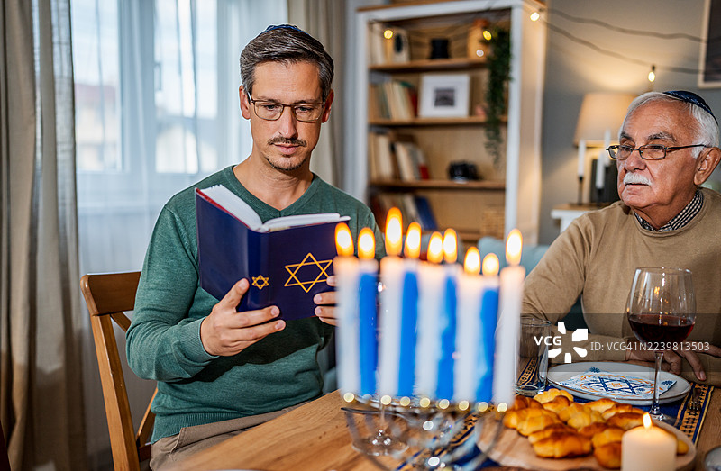 犹太家庭在家中庆祝光明节，同时阅读《托拉》。图片素材