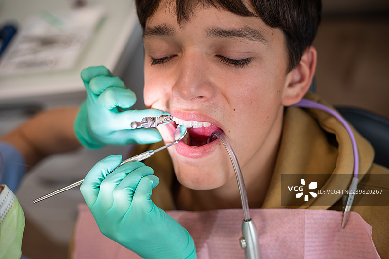 戴着手套的牙医使用牙科器械为年轻患者进行例行检查图片素材