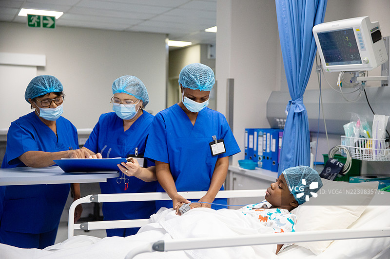 医护人员在讨论一名少女接受手术后在重症监护室的康复过程图片素材