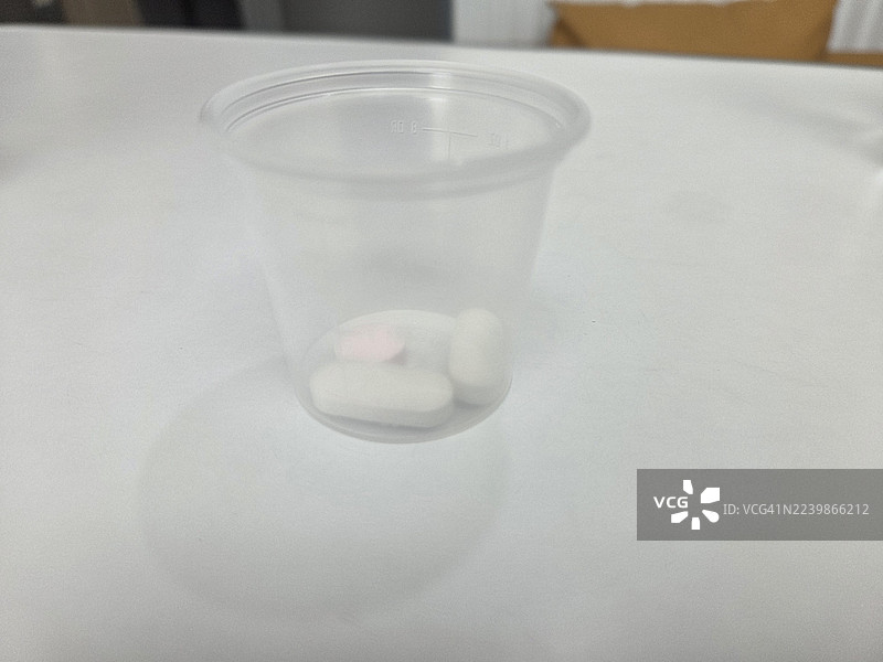 药片胶囊放在塑料杯里图片素材