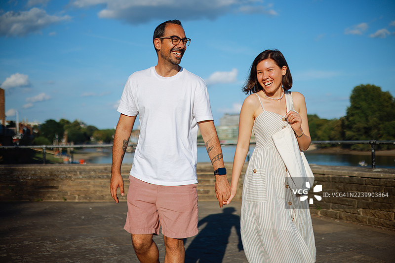 年轻情侣在哈默史密斯大桥背景下交谈并用锤子指点图片素材