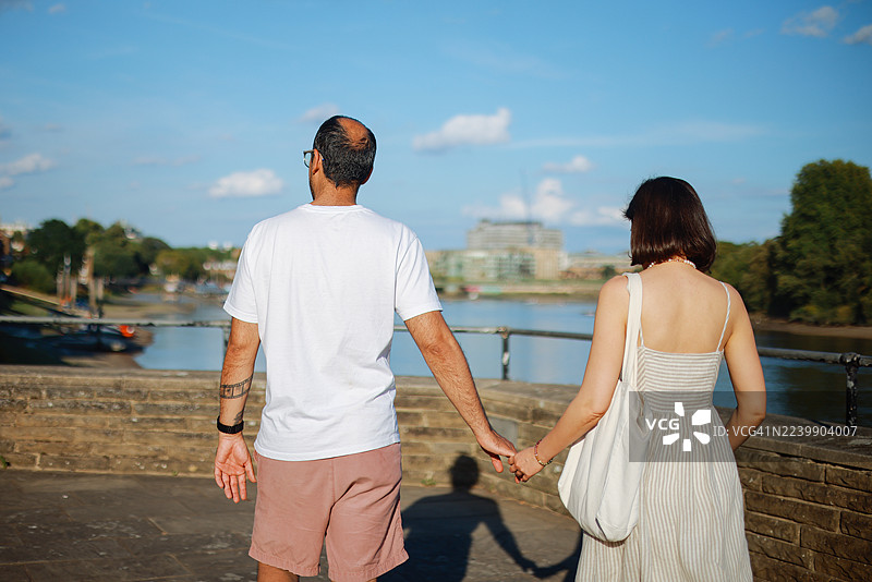 年轻夫妇在哈默史密斯桥背景下交谈并用锤子指点图片素材