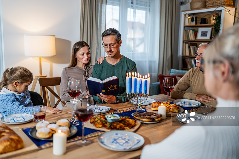犹太家庭在家中庆祝光明节，并阅读《托拉》。图片素材