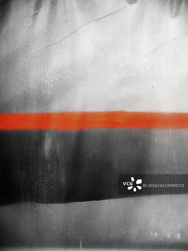 透过肮脏的窗户看到的揉皱的白色塑料防水布，上面有橙色胶带。阳光和阴影。自然色彩。比利时布鲁塞尔。图片素材