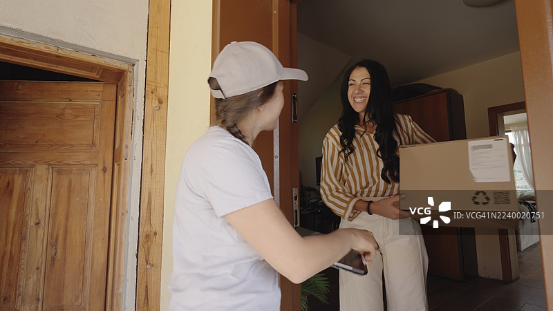 快递员在家中向客户递送包裹。电子商务图片素材