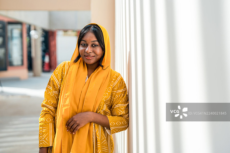 自信的黑人穆斯林女性身穿黄色阿巴亚微笑图片素材