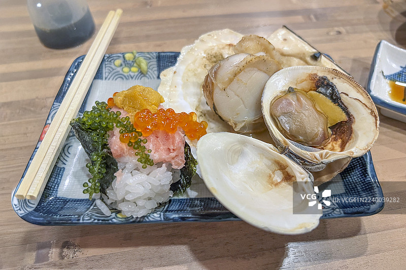 日式海鲜拼盘，包含烤扇贝、蛤蜊和寿司图片素材