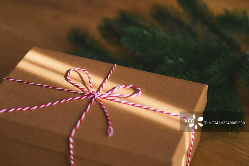 用牛皮纸包裹的温暖圣诞礼物，配有红麻绳和绿叶，营造节日气氛图片素材