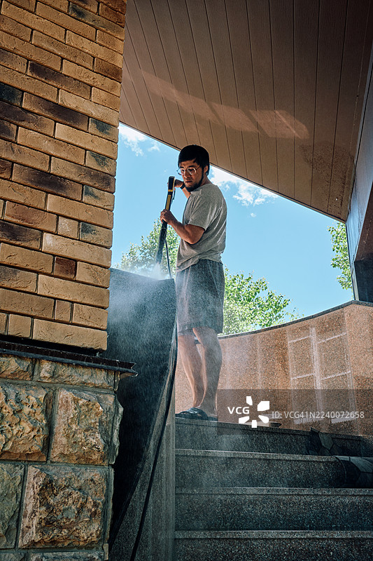 高压水枪清洁房屋庭院的男子图片素材