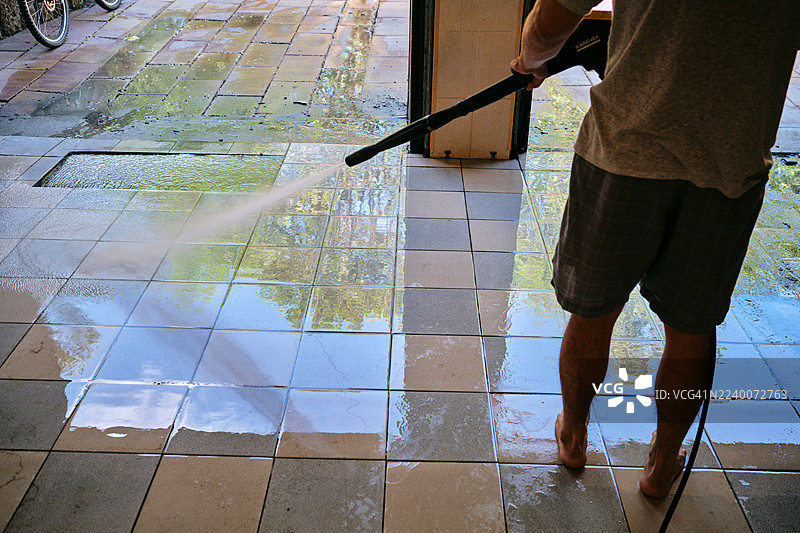 高压水枪清洁房屋周边区域的男人图片素材