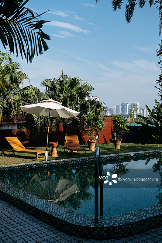 宁静的泳池边，配有躺椅和遮阳伞图片素材