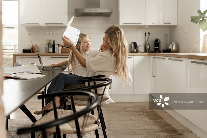 斯堪的纳维亚单身母亲和女儿在家中厨房审阅财务报表，同时还要应对单身母亲的挑战。图片素材