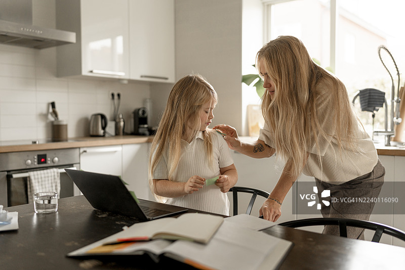 明亮的厨房里，母女在家中平衡着财务和学习。图片素材