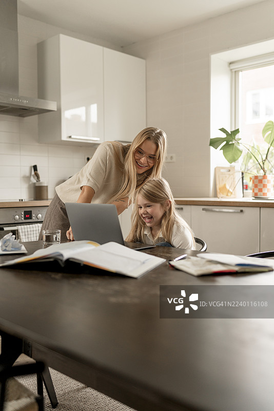 斯堪的纳维亚女性与孩子在家一起用笔记本电脑学习，在厨房里进行预算和学习。图片素材