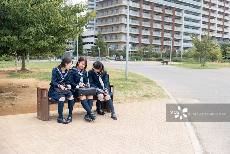 女高中生们通过智能手机观看电影，练习跳舞，并分享到社交媒体。图片素材