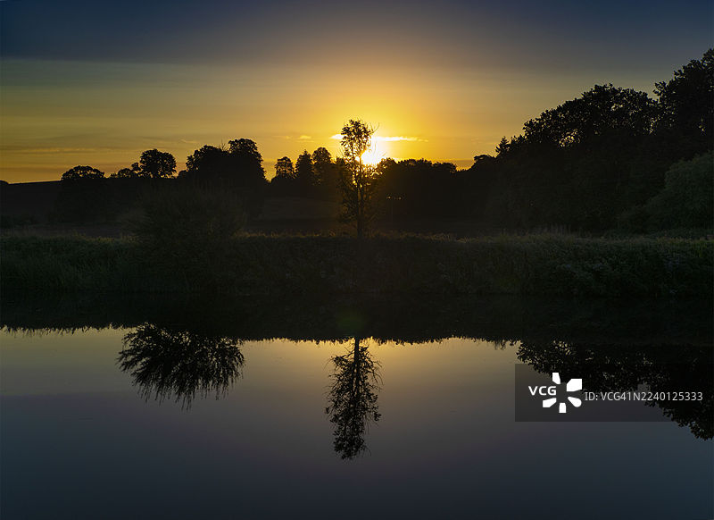 秋日黎明，独自的树木及其在拉德利船屋旁泰晤士河上的倒影图片素材