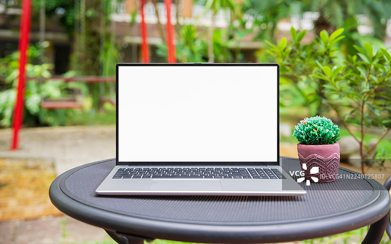 咖啡馆背景下桌子上的笔记本电脑空白屏幕。咖啡店模糊背景桌子上的笔记本电脑空白屏幕。图片素材