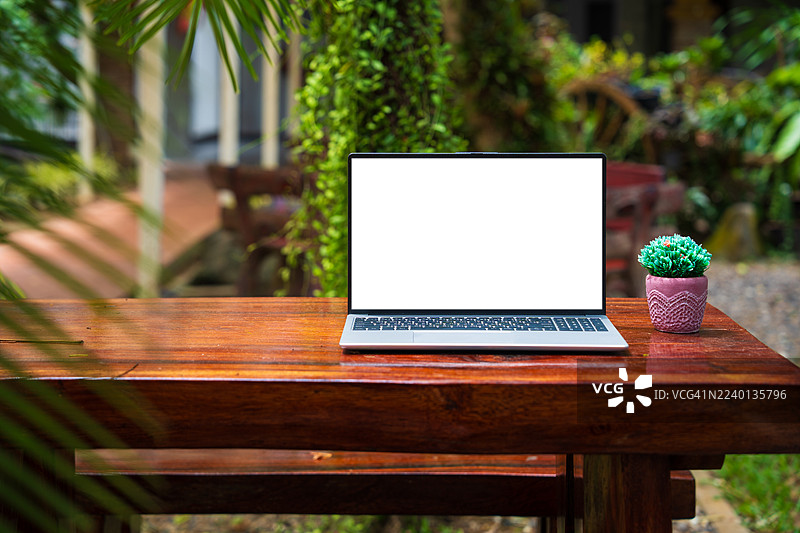 咖啡馆背景下桌子上的笔记本电脑空白屏幕。咖啡店模糊背景的桌子上的空白屏幕笔记本电脑图片素材