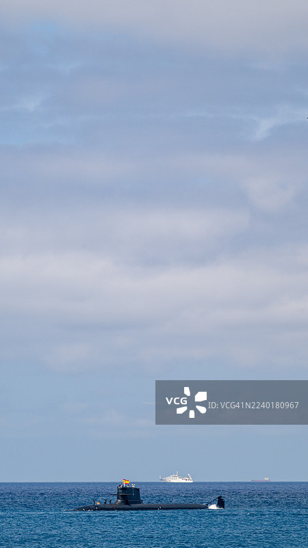 西班牙S-80 Plus级军用潜艇在白天航行于蓝色海洋水面，旗帜飘扬。图片素材