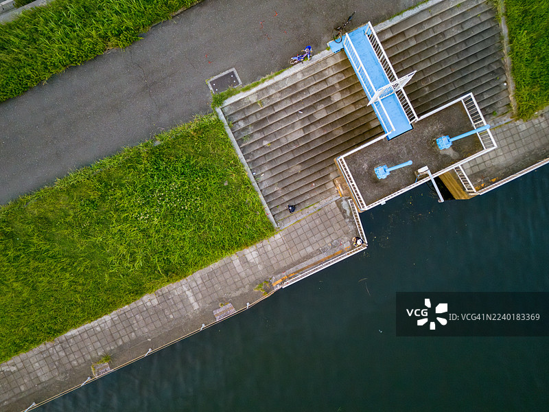 有人在散步。夕阳映照在河面上。河上有一座桥。鹤见川的无人机航拍。西边是横滨市鹤见区，东边是川崎市川崎区和幸区。图片素材