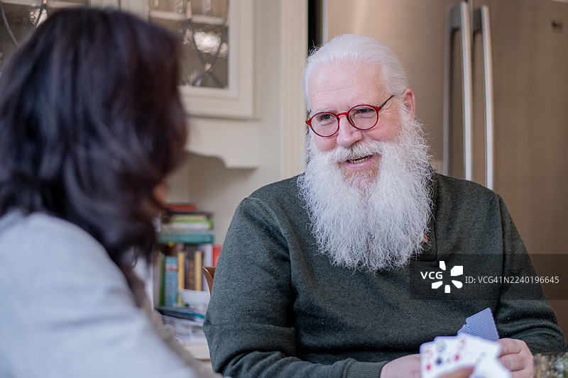 一位留着白胡子、戴着红眼镜的老人正在厨房里进行温馨的交谈图片素材