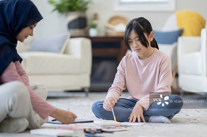 亚洲女孩和妈妈在舒适的客厅家庭场景中一起创作艺术图片素材