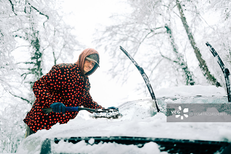 男人正在清理汽车挡风玻璃上的雪和冰图片素材