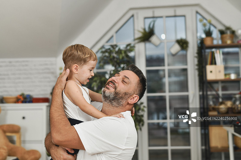 父亲在温馨的家中抱着孩子，展现了家庭的纽带和爱图片素材