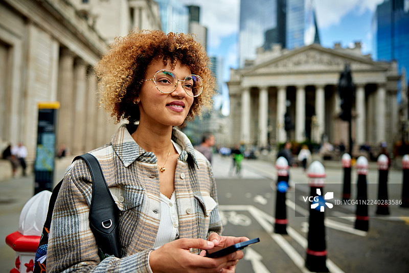 年轻女子在伦敦金融区使用智能手机图片素材