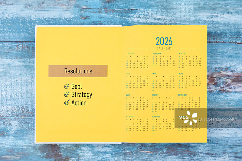 木质背景上打开的2026年日历和包含解决方案计划的日记本页面。图片素材