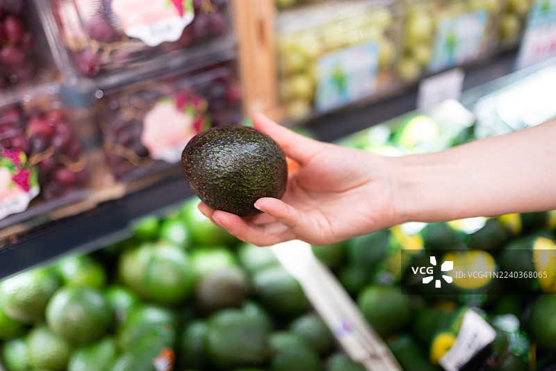 在超市的水果区挑选牛油果图片素材