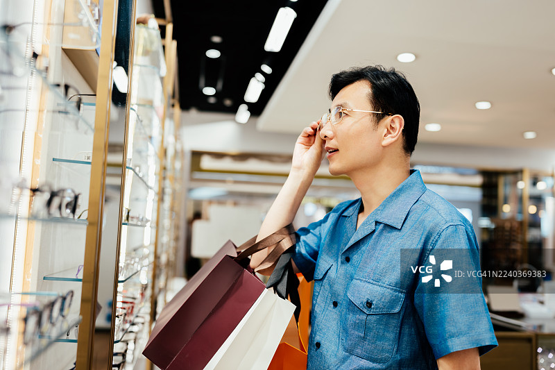 年轻的亚洲商人正在眼镜店挑选眼镜。图片素材