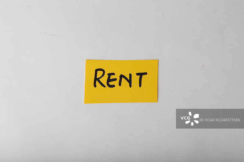 一张黄色的便利贴，上面写着“租金”，放在白色表面上，暗示着租赁机会图片素材