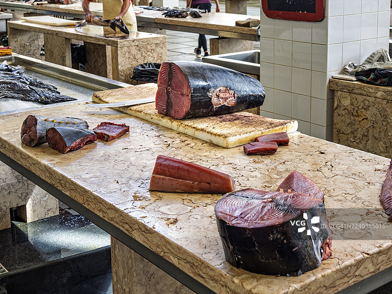 传统零售市场里，鱼贩的柜台上摆放着待售的金枪鱼块。图片素材