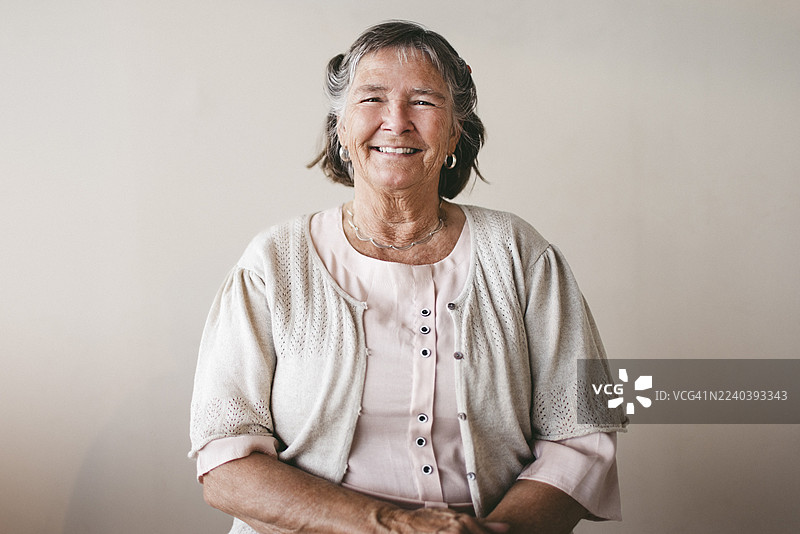 背景为米色的微笑短发老年女性肖像图片素材