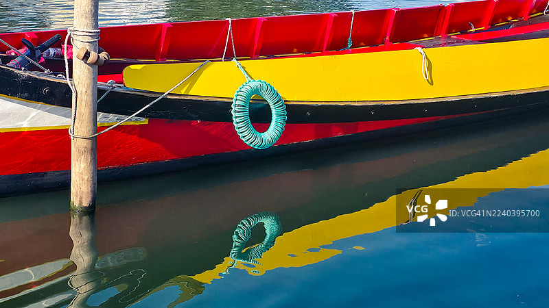 黄红相间的渔船倒映在波光粼粼的蓝色水面上图片素材