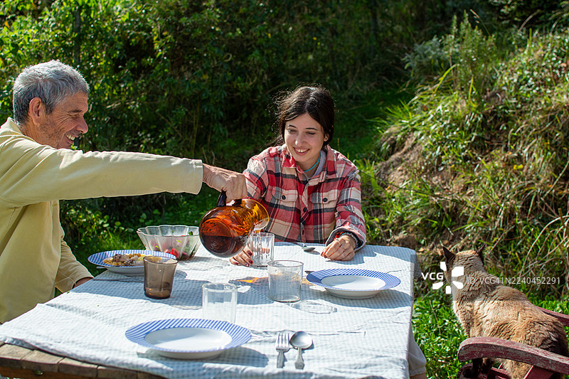 父亲在户外家庭聚餐时为女儿倒饮料图片素材