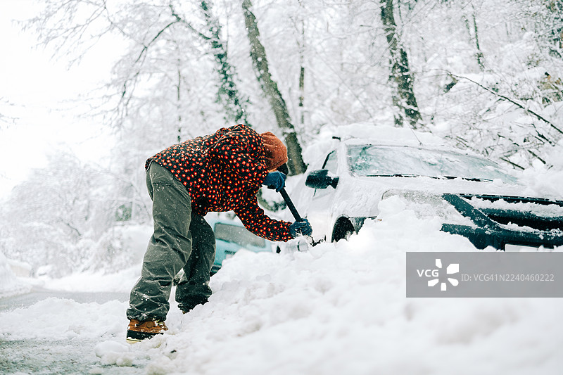 暴风雪过后，男子正在铲除汽车上的积雪图片素材