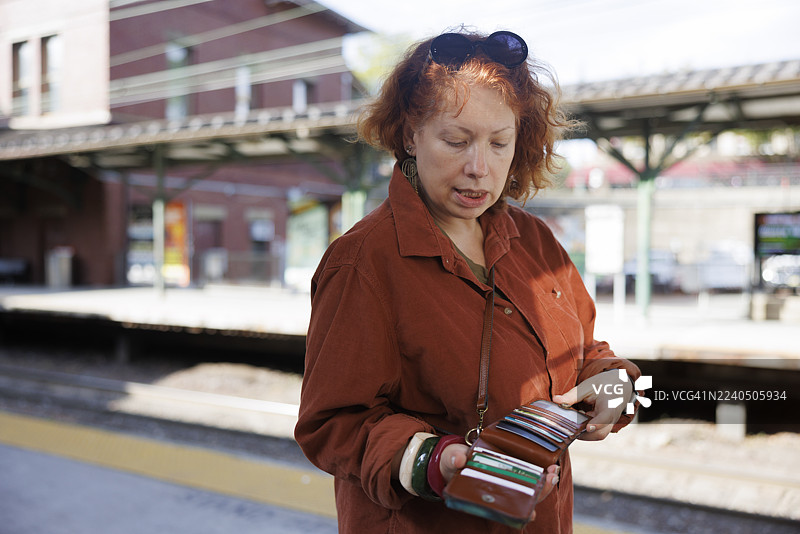 女子在新泽西火车站查看钱包里的物品。日常通勤者在登车前整理交通卡和票据。图片素材