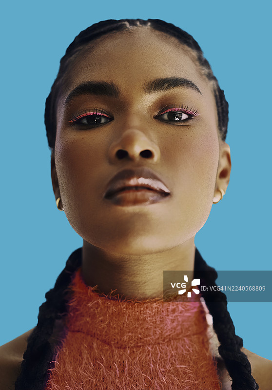 自信的黑人女性，化着浓妆，编着辫子，背景为蓝色。图片素材