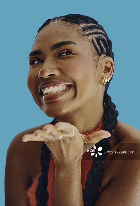 身着非洲裔美国女性，留着编发，在极乐蓝背景下微笑图片素材