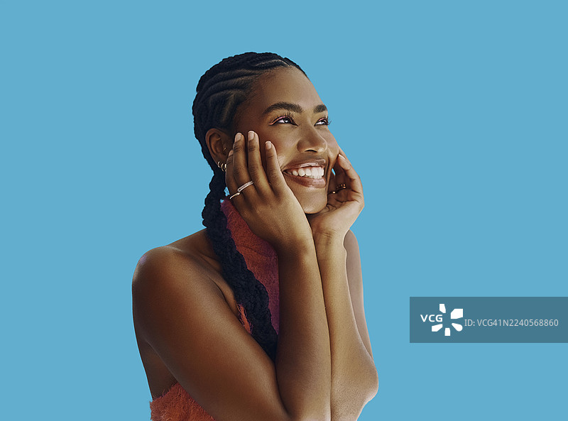 蓝背景上，一位快乐的黑人女性带着幸福的表情微笑。图片素材
