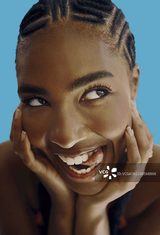 喜悦的黑人女性，面带俏皮的表情，在极乐蓝色的背景前微笑图片素材