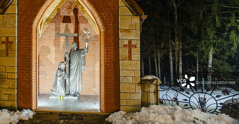 夜晚的宗教圣地，耶稣手持十字架和皇冠的雕像以及跪拜的圣母玛利亚雕像被照亮，雪地景观唤起了信仰、虔诚和希望。

Translation Analysis:
- The translation accurately captures the elements of the original description:图片素材