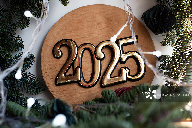 新年2025。新年快乐。圣诞假期。2025新年的数字，背景为纯色，带有圣诞树枝。节日背景。图片素材