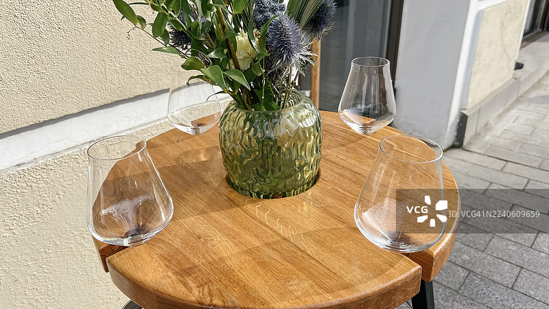 人行道酒店酒吧角落的桌子，摆放着水晶玻璃器皿和鲜花图片素材