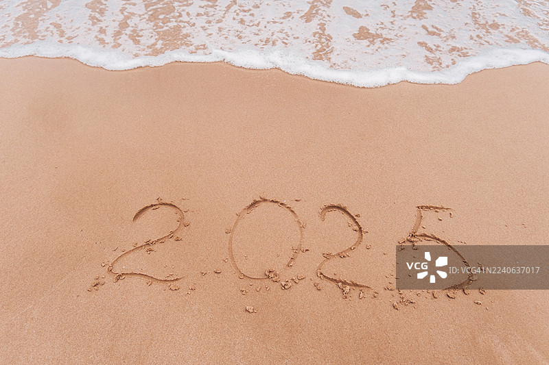海浪冲刷着写在沙滩上的2025字样图片素材