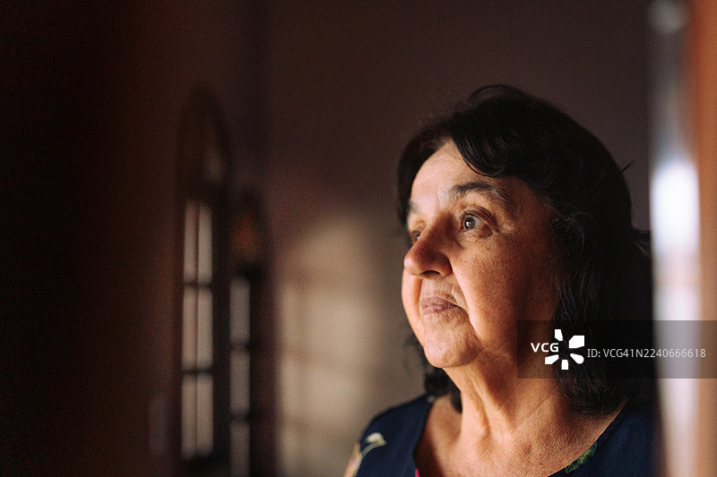 一位年长的胖女人肖像，看向窗外图片素材