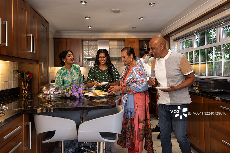 一家人在厨房里围着蛋糕分享温馨时刻图片素材