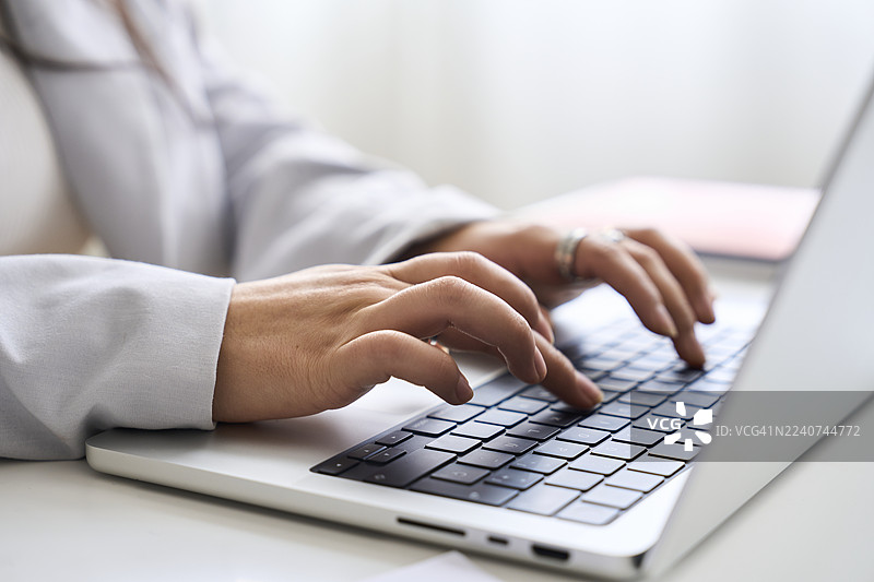 女人在家工作的双手正在敲击笔记本电脑键盘图片素材